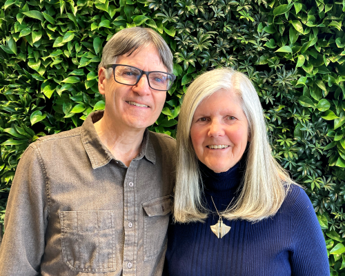 Portrait of Pete and Nancy in front of a wall of greenery